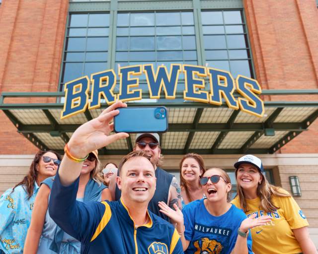 A group of Brewers fans smile in front of American Family Field