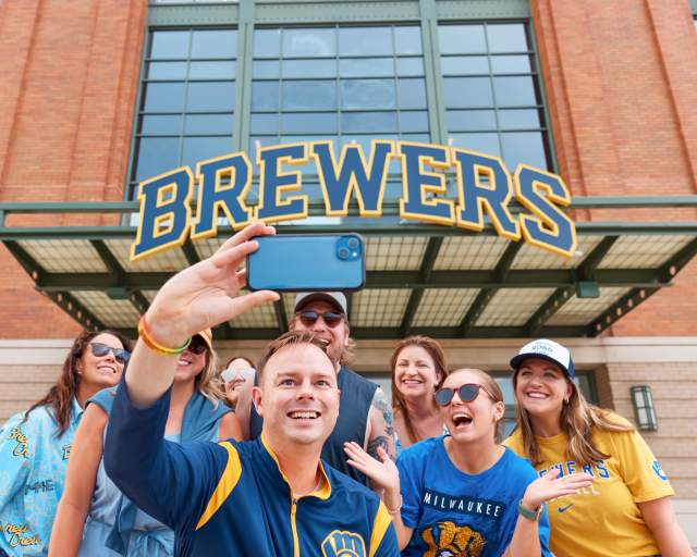 A group of Brewers fans smile in front of American Family Field