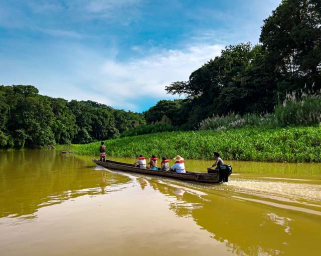 Emberá-Wounaan community traveling by dugout canoe along a river in the Panamanian rainforest