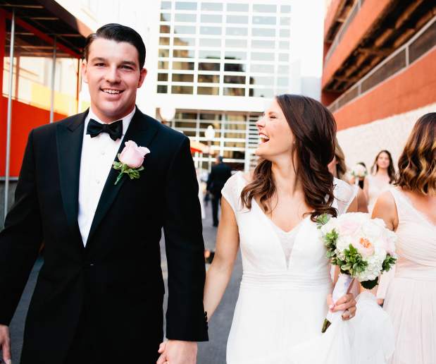 Bride and Groom Walk out of their Venue Holding Hands and Smiling