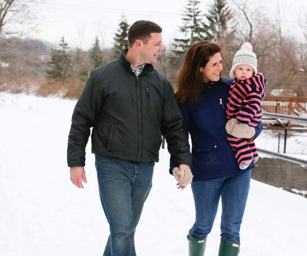 Couple with Baby Holding Hands and Walking through the Snow