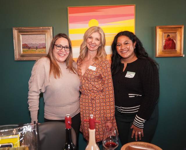 Three women standing close together and smiling