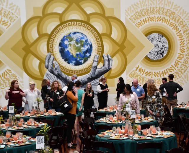 Tables set for lunch with people standing around them and art in the background