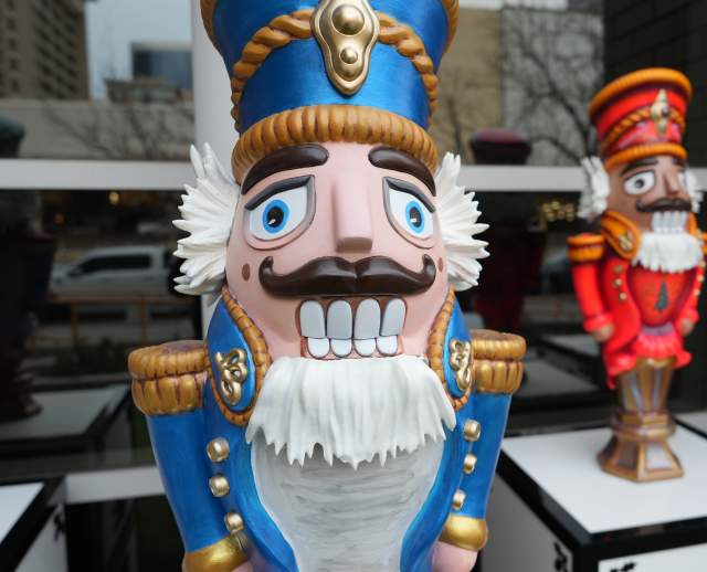 A classic nutcracker statue in a blue uniform with another nutcracker in red in the background