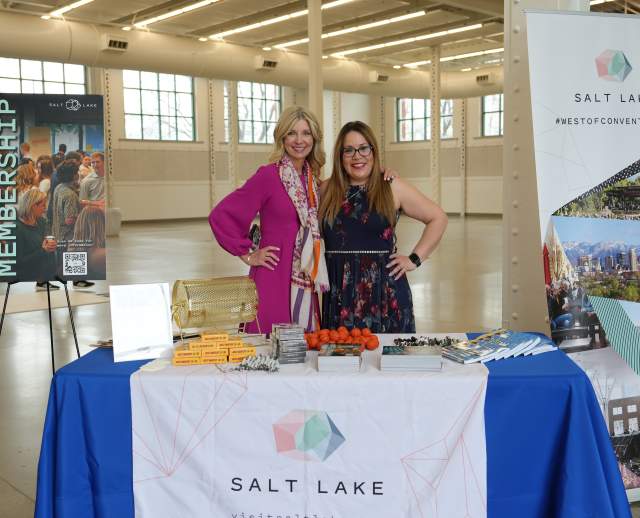 Kim Stowe and Cristina Chavez standing behind a table with a Visit Salt Lake logo drape and a sign that says The Power of Membership