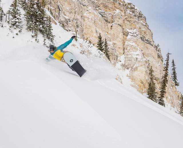Snowboarder wearing blue and yellow jacket at Solitude Mountain
