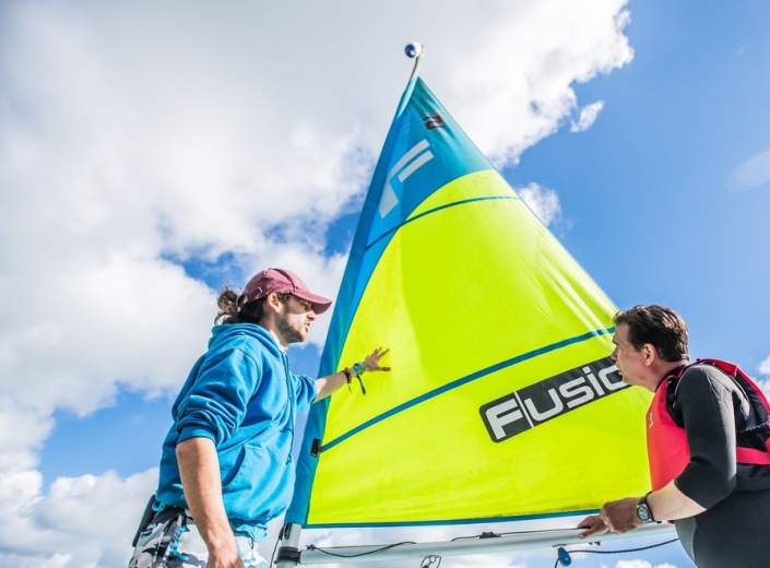 two men in front of a sailing boat
