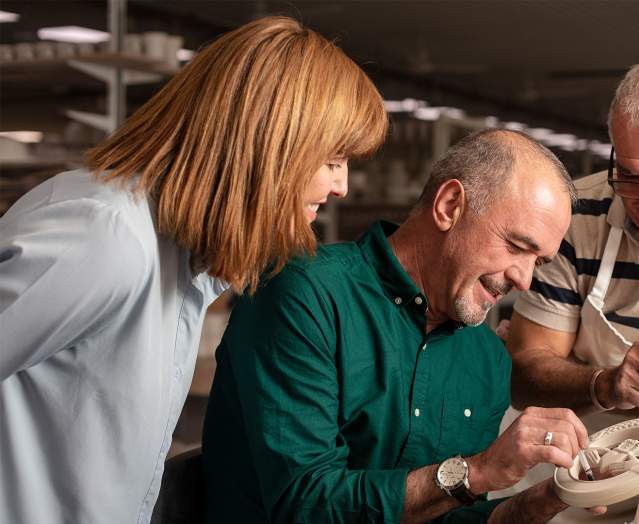A man and woman being shown how to paint pottery as part of the tour at Belleek Pottery Visitor centre.