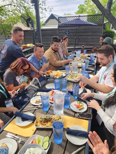 Group of Young professionals dining on the patio at The Yard as server puts food on the table