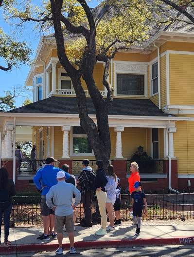 Historic district walking tour - people staying in front of a big old yellow home