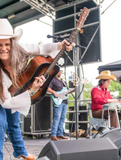 Female guitarist on stage, smiling at the camera