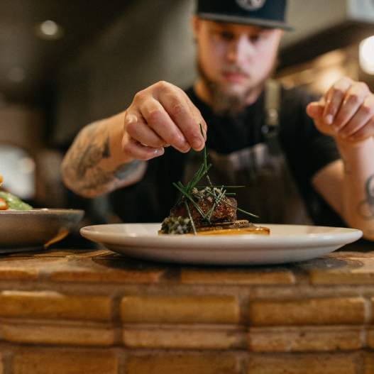 Chef puts finishing garnishes on a dish at Marche.