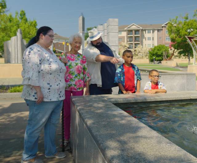Multi-generational family gathered around the reflection pool in Fayetteville's Veterans' Park