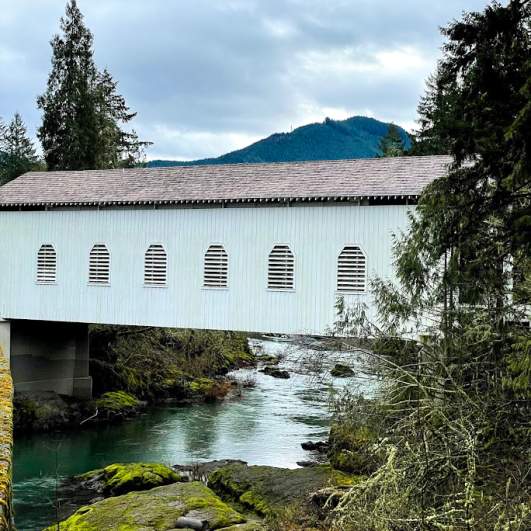 a white covered bridge spans a river