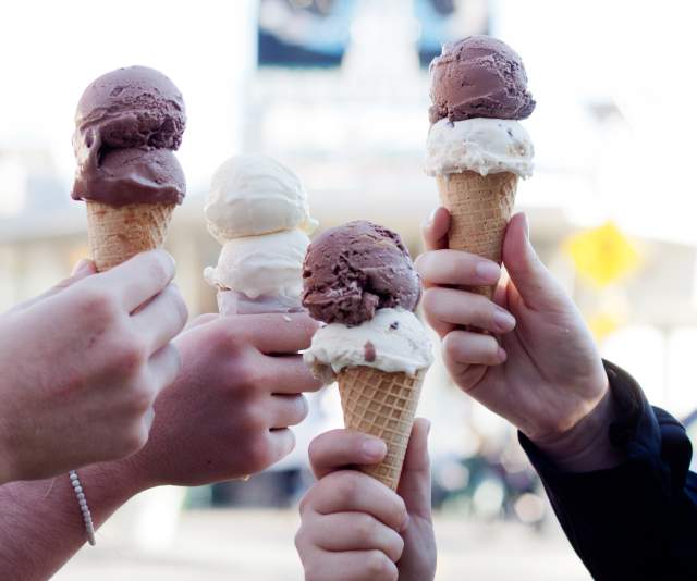 Four hands holding double-scoop ice cream cones