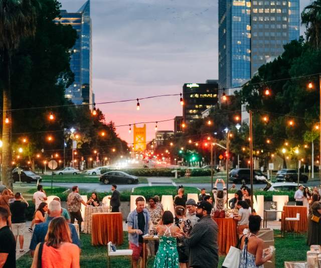 people outdoors at an evening wine event with the tower bridge in the background
