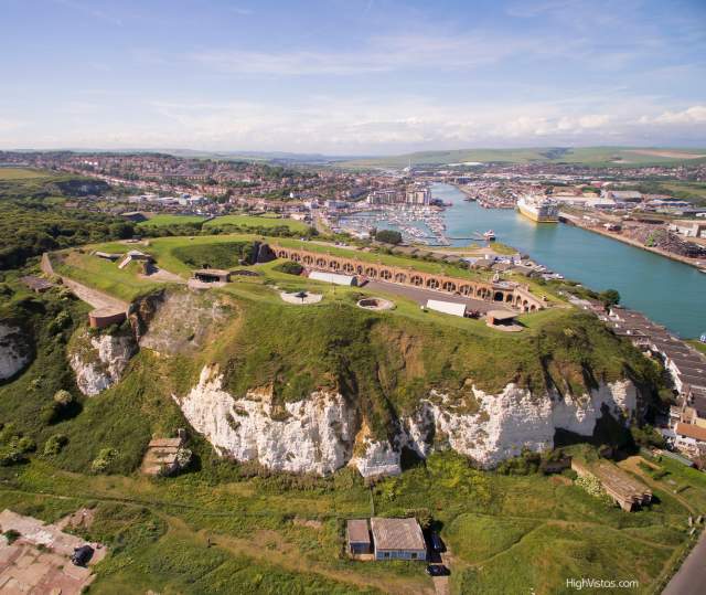 Aerial view of the grounds and red brick buildings of Newhaven Fort with sea in the distance