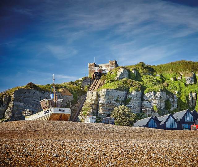 Shingle beach and fishing boat in Hastings Old Town, with cliffside lift in the background