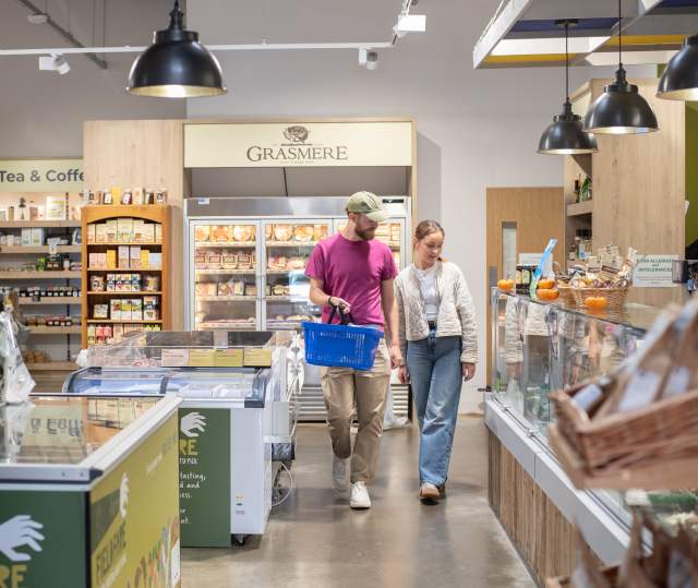 two people in farm shop with basket in hand surrounded by local produce