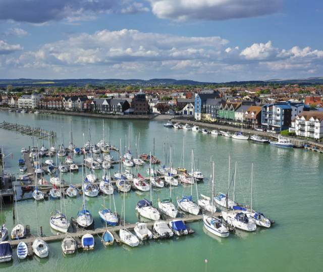 Yachts moored on the river at Littlehampton harbour, with riverside apartments on the opposite side