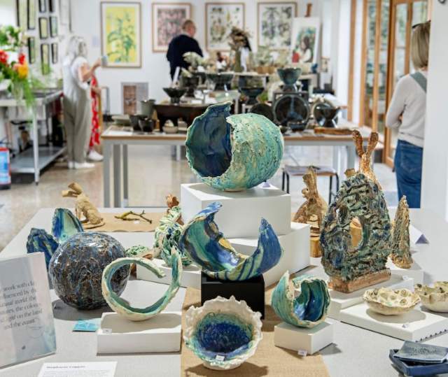 An exhibition space with pottery displays and people in background