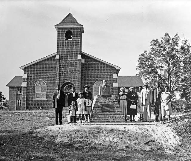 black and white photo of a group of people standing in front of a church