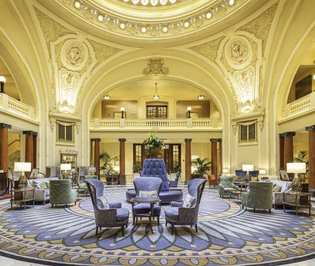 Ornate historical lobby with seating in the middle and a round skylight