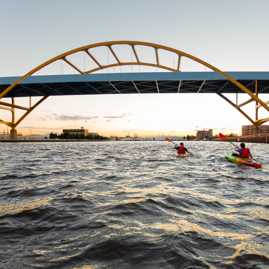 two kayakers kayaking under the Hoan Bridge