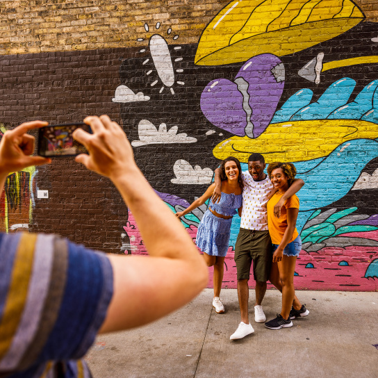 friends taking a picture in front of a colorful mural