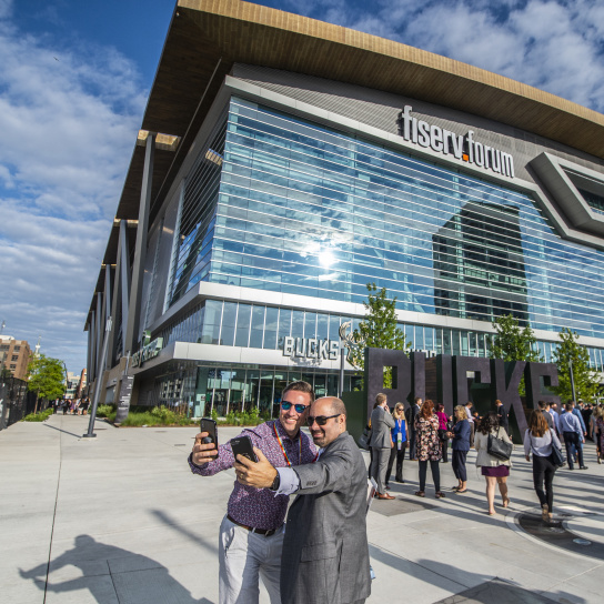 meeting attendees taking a selfie in front of Fiserv Forum during Northwestern Mutual's annual meeting