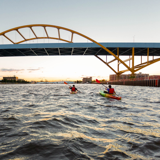 two kayakers kayaking under the Hoan Bridge