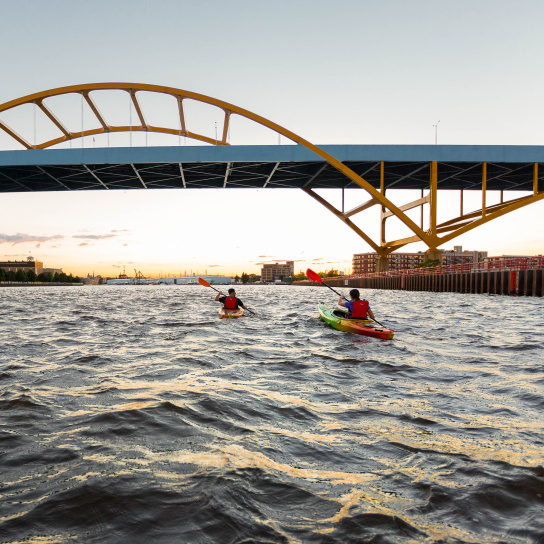 two kayakers kayaking under the Hoan Bridge