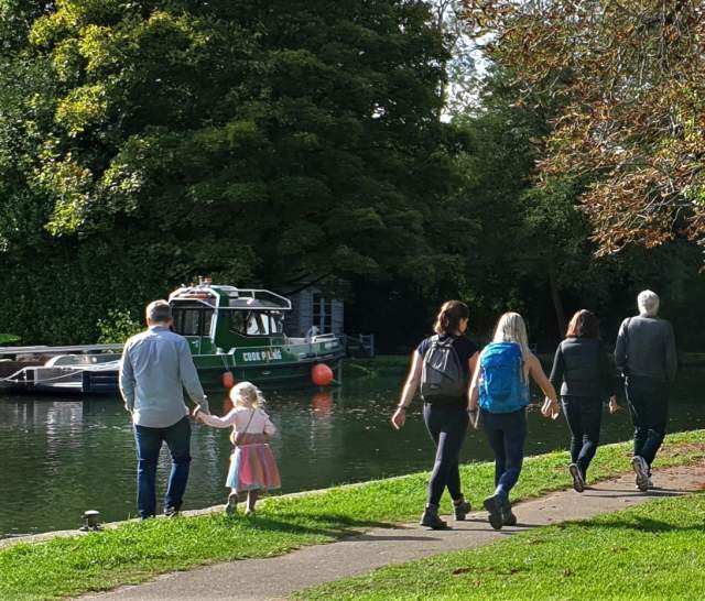 People walking along the Thames Path along the river.