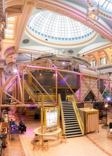 Inside the Royal Exchange Theatre with theatre space in the centre of the room and chairs and tavles set up outside
