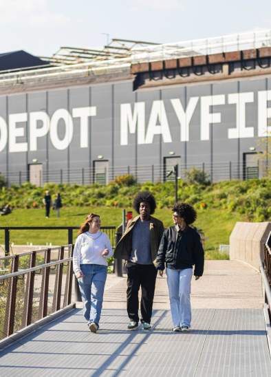 Friends walking along a bridge at Mayfield Park with Depot Mayfield sign in the background