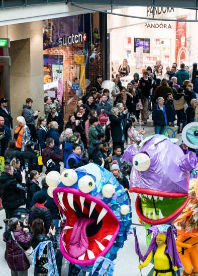 Procession of people in Halloween outfits through crowd in a shopping centre