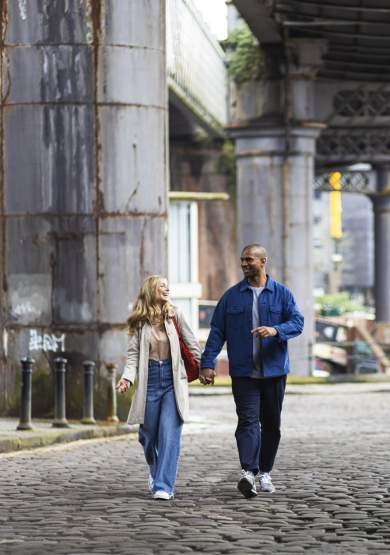 People walking under bridges on cobbles streets in Manchester