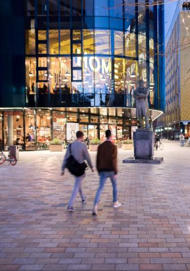 2 people walking in a square in front of HOME venue.