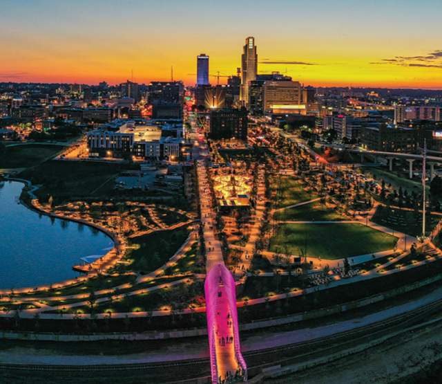 A vibrant sunset skyline shot of Omaha, Nebraska showing pink lights from Heartland of America Park and Farnam Pier.