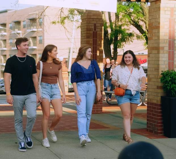 Four young adults smile and enjoy a walk through downtown Overland Park.