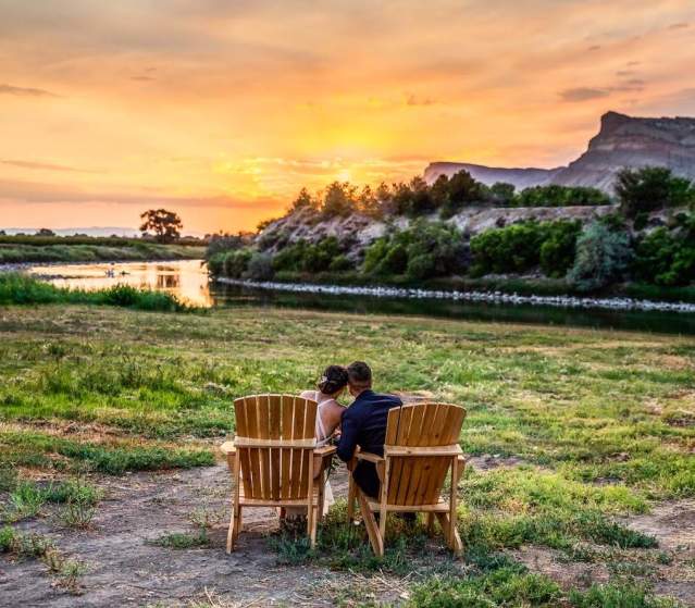 Married couple sits and watches the sunset on the banks of the Colorado River