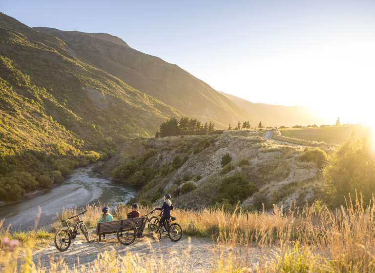 A group of cyclists taking a break next to Gibbston River