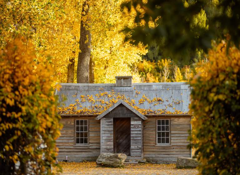 A historic cottage surrounded by yellow, orange and green foliage