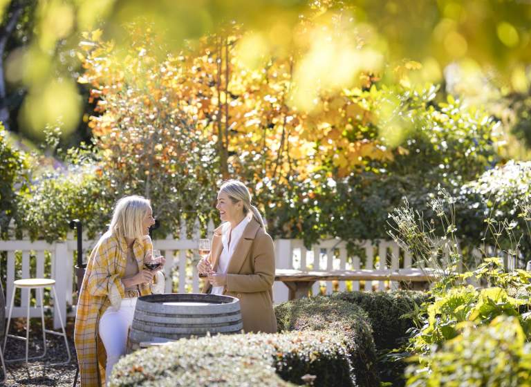 Women sitting in restaurant garden drinking wine