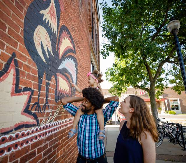 Family exploring downtown mural of Polish Chickens