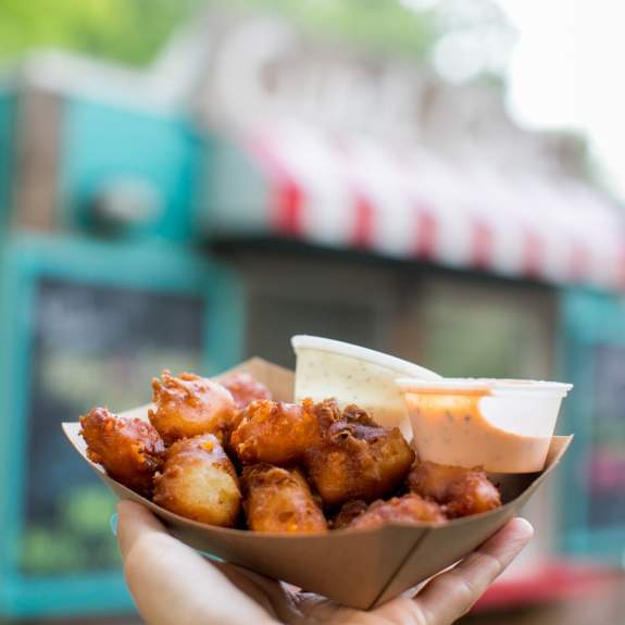 A basket of cheese curds in front of a cheese curd food stand