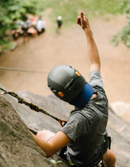 Man rock climbing on a cliff giving a thumbs up