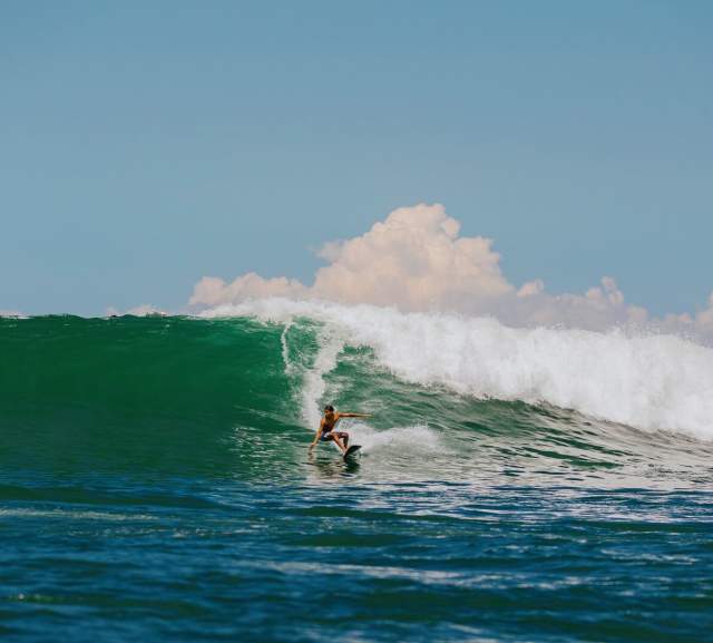 Surfer maneuvering a large wave in Panama with deep blue ocean