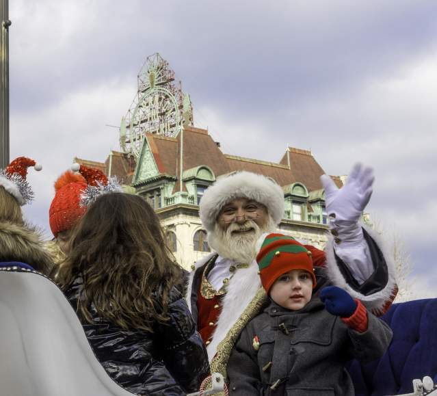 Santa and child waiving while sitting in a sleigh