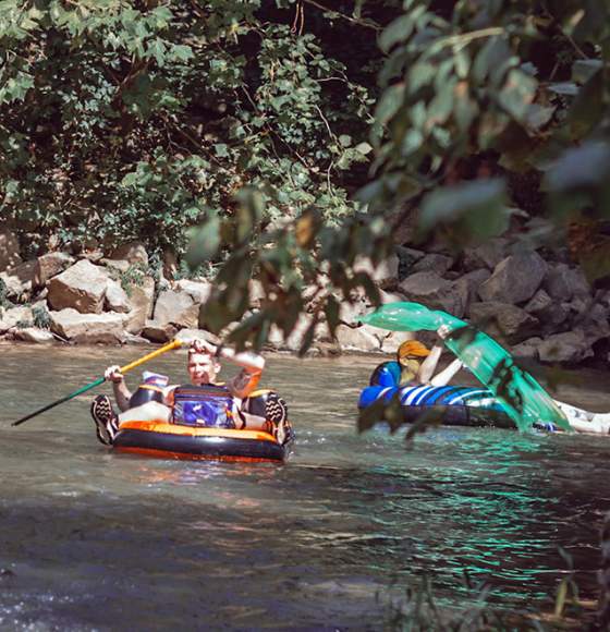 3 guys tubing on a river